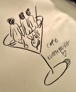 A black ink line drawing of three women perched on the edge of a martini glass.